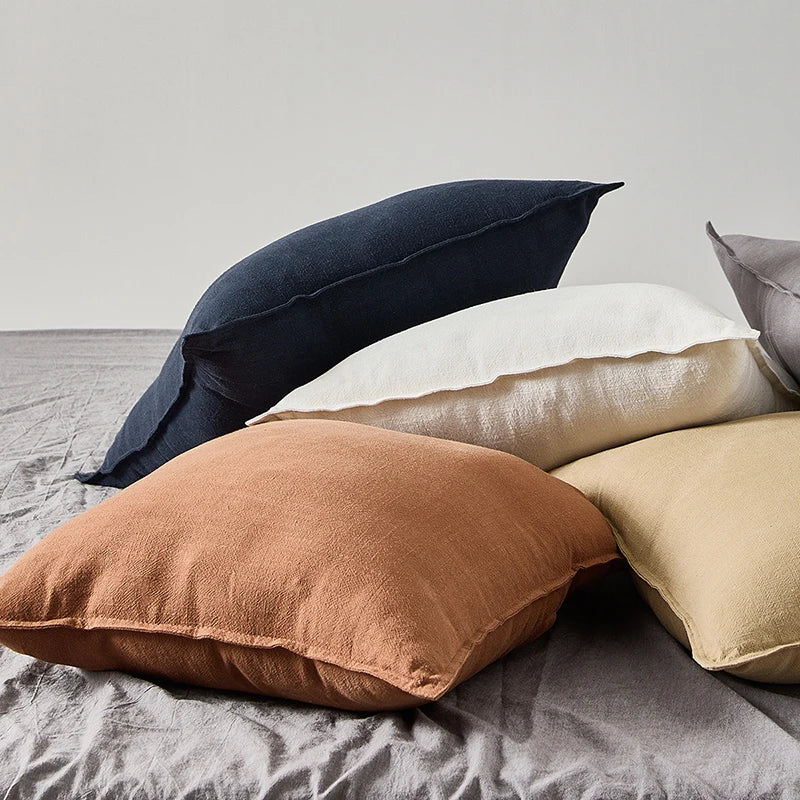 Cotton-ramie cushion covers in rust, cream and navy on a bed